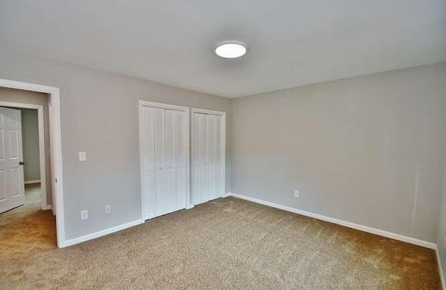 6500 Gaines Ferry Rd Unit A2, Flowery Branch, GA 30542 - unfurnished bedroom featuring carpet, baseboards, and two closets