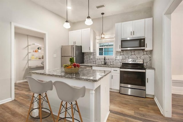 kitchen with sink, white cabinets, dark stone countertops, a kitchen island, and stainless steel appliances