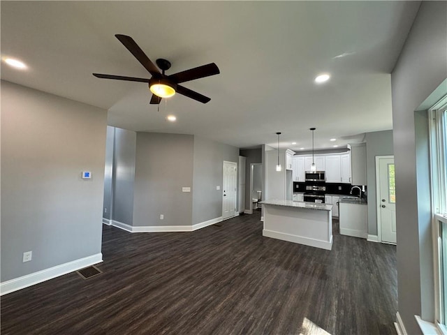 unfurnished living room featuring dark hardwood / wood-style floors, ceiling fan, and sink