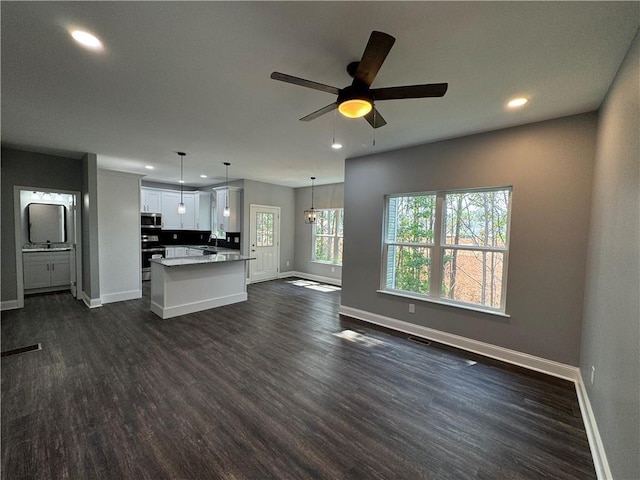 unfurnished living room featuring ceiling fan, sink, and dark hardwood / wood-style flooring