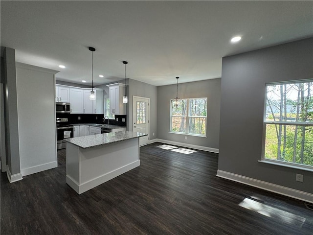 kitchen with white cabinetry, stainless steel appliances, decorative light fixtures, dark hardwood / wood-style floors, and sink