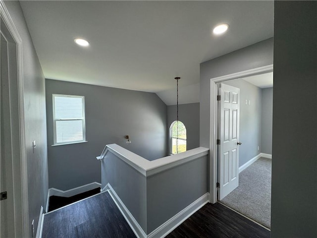 hall featuring dark carpet and vaulted ceiling