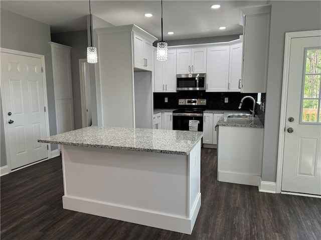 kitchen with hanging light fixtures, white cabinetry, sink, and stainless steel appliances