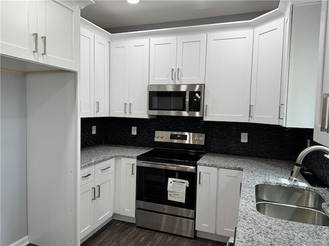 kitchen featuring white cabinetry, dark wood-type flooring, light stone countertops, stainless steel appliances, and sink