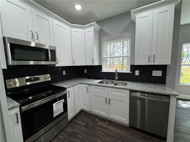 kitchen featuring light stone counters, dark wood-type flooring, sink, white cabinetry, and stainless steel appliances