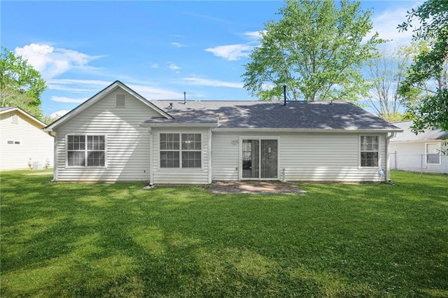 back of property featuring fence, a lawn, and roof with shingles