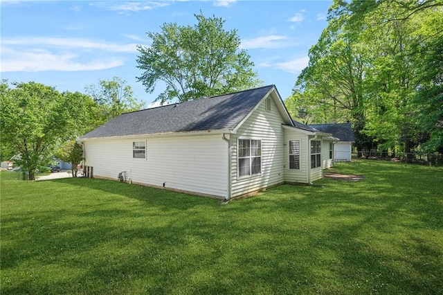 exterior space featuring a yard, fence, and a shingled roof