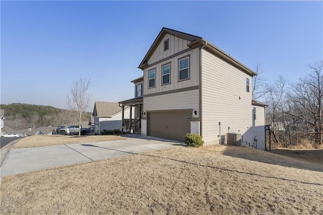 view of side of property featuring central AC, board and batten siding, concrete driveway, and an attached garage