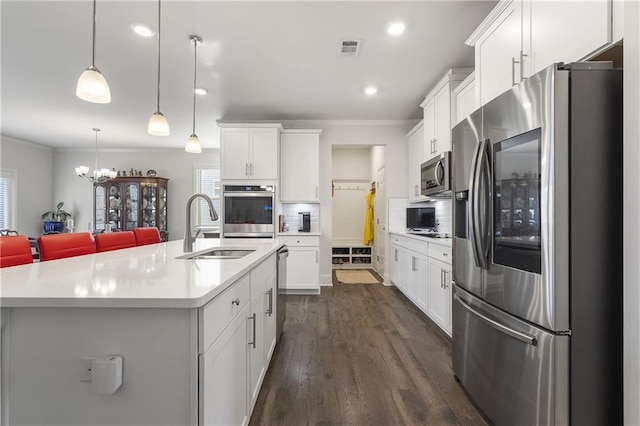 kitchen with a sink, visible vents, appliances with stainless steel finishes, and ornamental molding