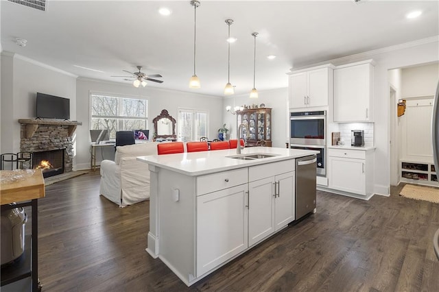 kitchen with a ceiling fan, stainless steel double oven, a sink, light countertops, and crown molding