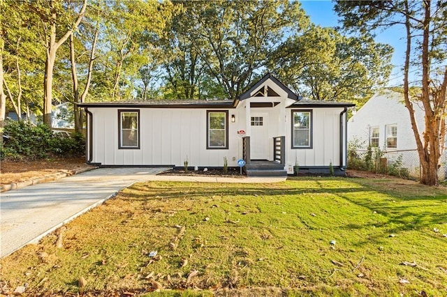 view of front of house featuring a front lawn, board and batten siding, and fence