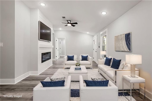 living area with baseboards, wood finished floors, a glass covered fireplace, and recessed lighting