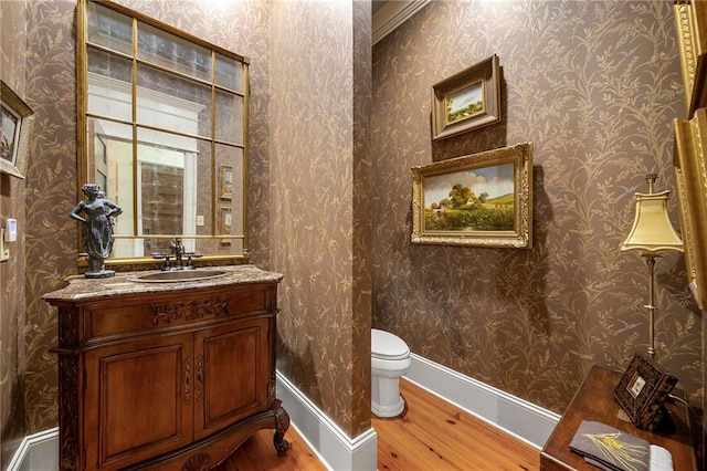 bathroom featuring hardwood / wood-style floors, ornamental molding, vanity, and toilet