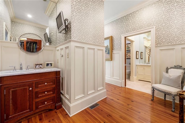 bathroom featuring hardwood / wood-style floors, ornamental molding, vanity, and toilet