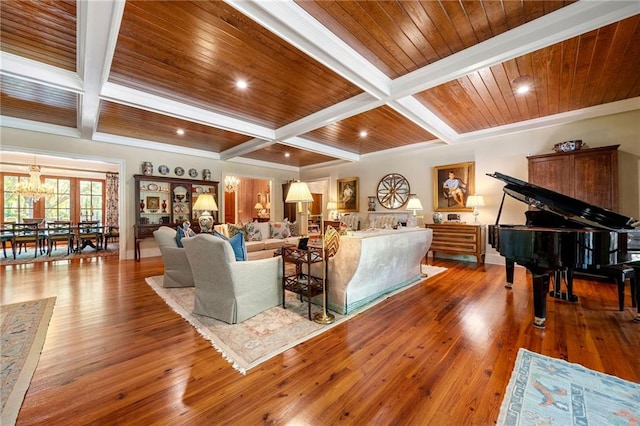 living room featuring wood-type flooring, beam ceiling, a notable chandelier, and coffered ceiling