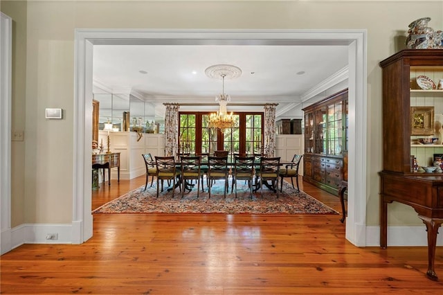 dining space with ornamental molding, hardwood / wood-style flooring, and an inviting chandelier