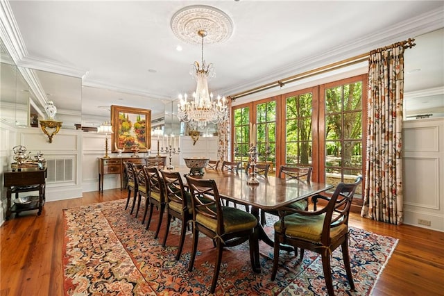 dining area featuring hardwood / wood-style flooring, an inviting chandelier, and crown molding