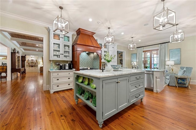 kitchen with tasteful backsplash, pendant lighting, a center island with sink, and light wood-type flooring