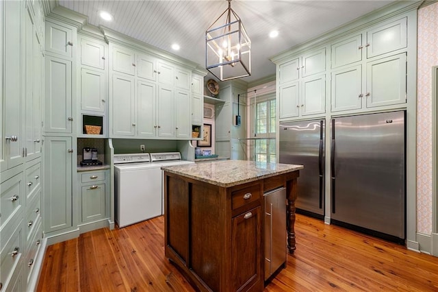 kitchen featuring light hardwood / wood-style flooring, separate washer and dryer, pendant lighting, a center island, and a chandelier