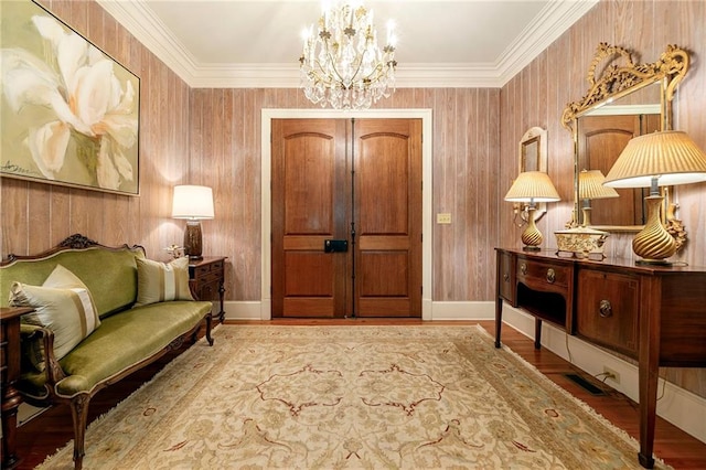 sitting room featuring wood-type flooring, wood walls, and a notable chandelier