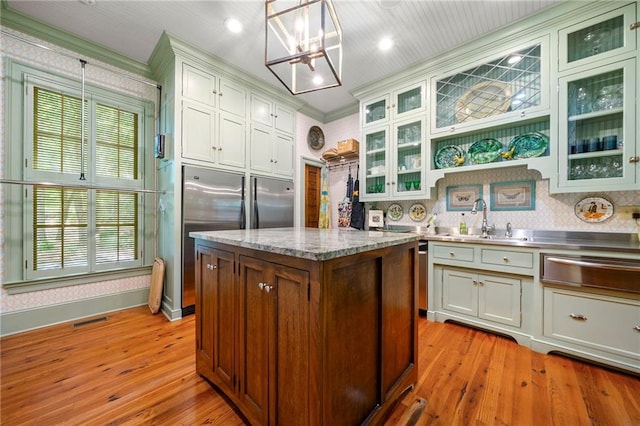 kitchen with sink, light hardwood / wood-style flooring, crown molding, and pendant lighting