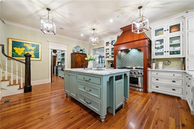 kitchen featuring backsplash, stainless steel range, white cabinets, and hardwood / wood-style floors