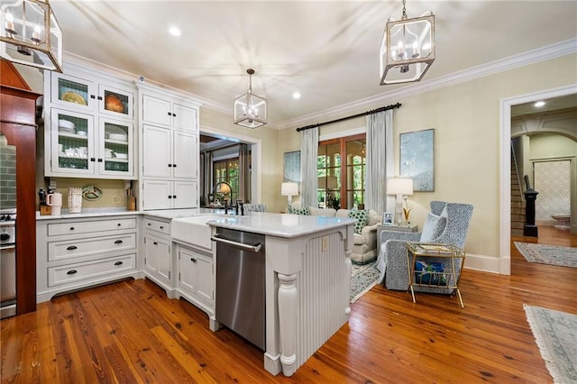 kitchen featuring stainless steel dishwasher, hanging light fixtures, hardwood / wood-style flooring, and white cabinets