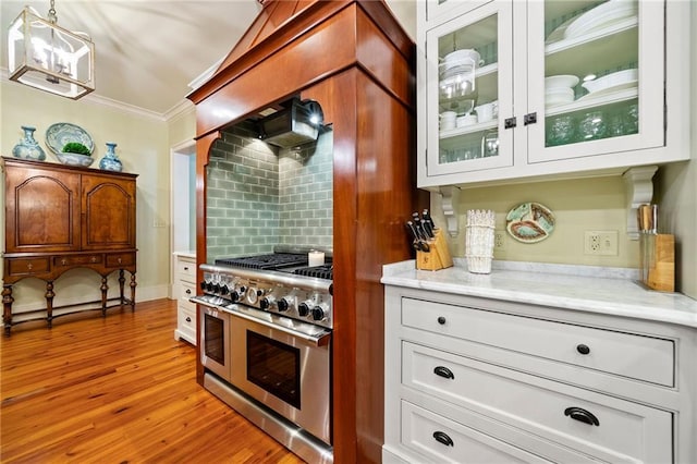 kitchen with hanging light fixtures, double oven range, tasteful backsplash, hardwood / wood-style flooring, and white cabinetry