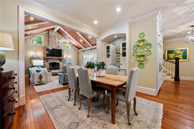 dining space featuring hardwood / wood-style flooring, plenty of natural light, lofted ceiling with beams, and a fireplace