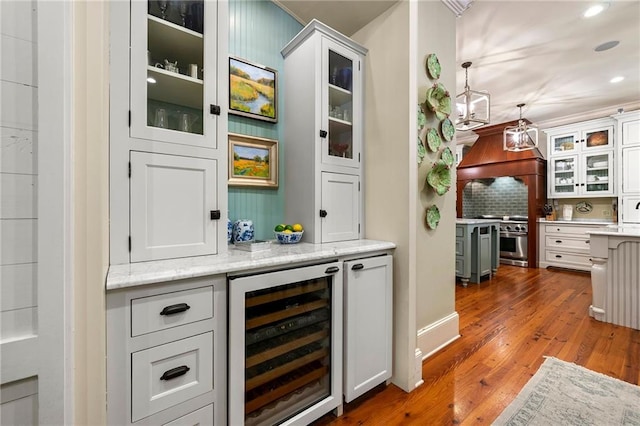 bar with stove, hanging light fixtures, beverage cooler, hardwood / wood-style floors, and tasteful backsplash