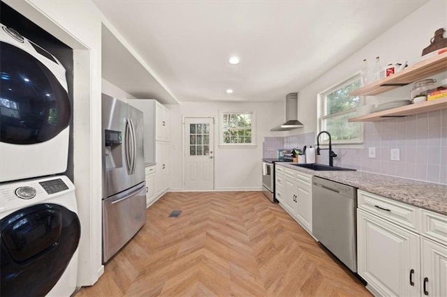 1649 Beecher St SW, Atlanta, GA 30310 - kitchen with appliances with stainless steel finishes, wall chimney range hood, stacked washer / dryer, a sink, and white cabinets