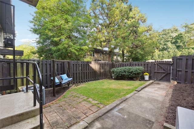 view of yard with a patio, a fenced backyard, and a gate