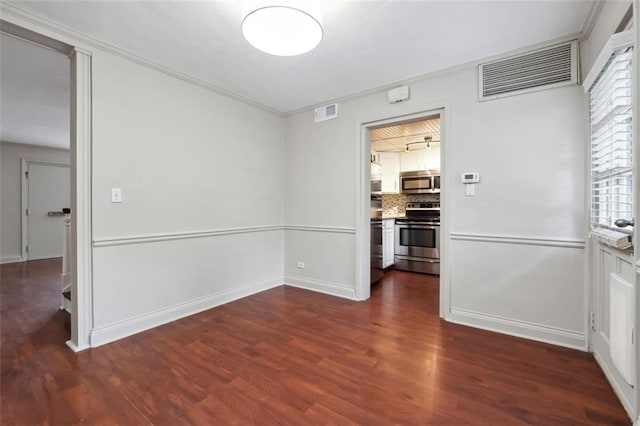 empty room featuring visible vents, baseboards, and dark wood finished floors