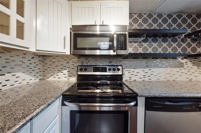 kitchen with glass insert cabinets, tasteful backsplash, appliances with stainless steel finishes, and white cabinets