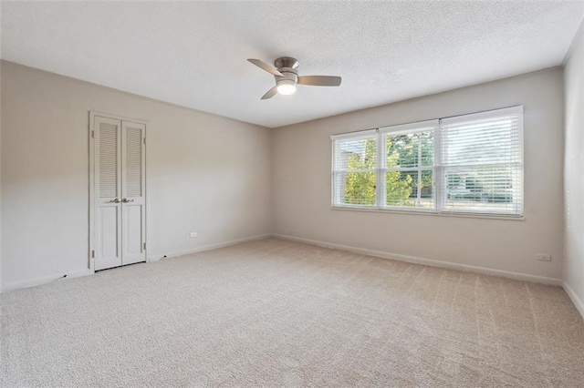 spare room with baseboards, carpet, ceiling fan, and a textured ceiling