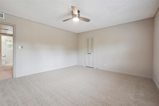 spare room with visible vents, light colored carpet, and ceiling fan