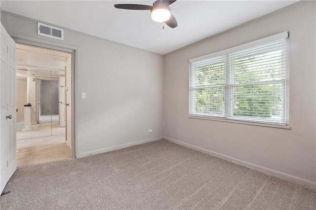 unfurnished room featuring visible vents, light carpet, baseboards, and ceiling fan