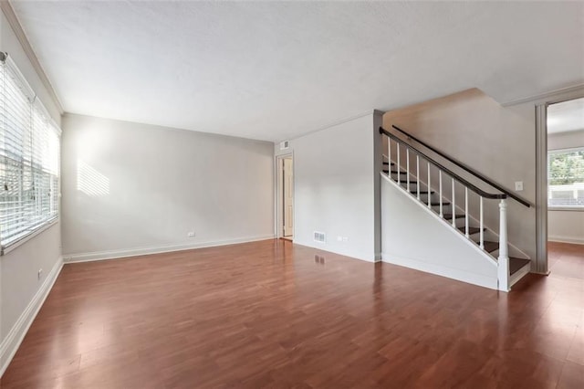 unfurnished living room featuring stairway, baseboards, visible vents, and wood finished floors