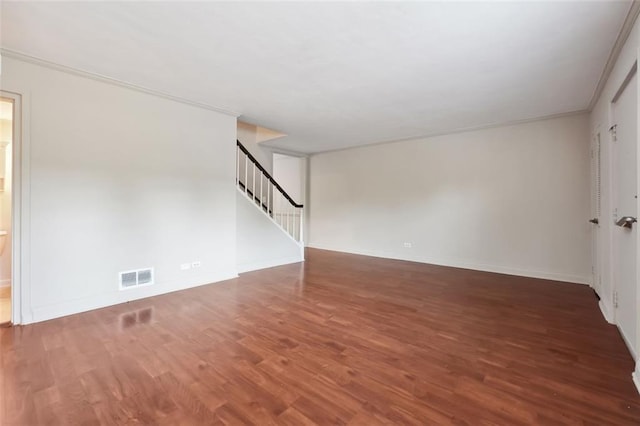 unfurnished room with visible vents, stairway, baseboards, and wood finished floors