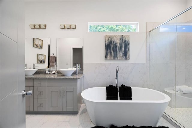 1463 Macklone St NE, Atlanta, GA 30307 - bathroom featuring marble look tile flooring, double vanity, a shower stall, a freestanding tub, and tile walls