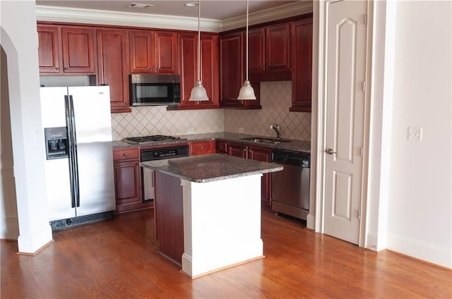 kitchen featuring sink, tasteful backsplash, a kitchen island, pendant lighting, and stainless steel appliances