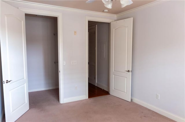 unfurnished bedroom with crown molding, light carpet, ceiling fan, and a closet