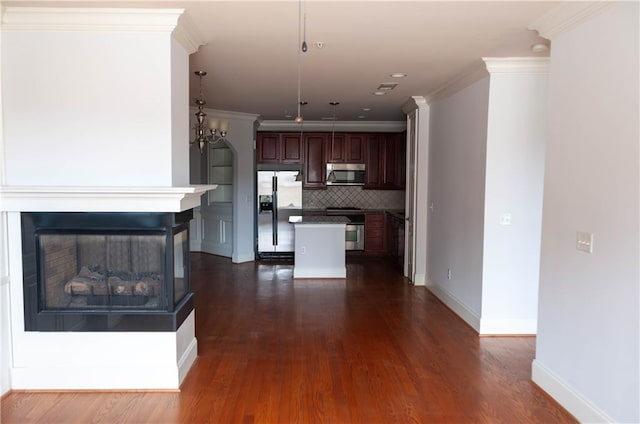 kitchen featuring dark wood-type flooring, appliances with stainless steel finishes, a center island, a multi sided fireplace, and tasteful backsplash