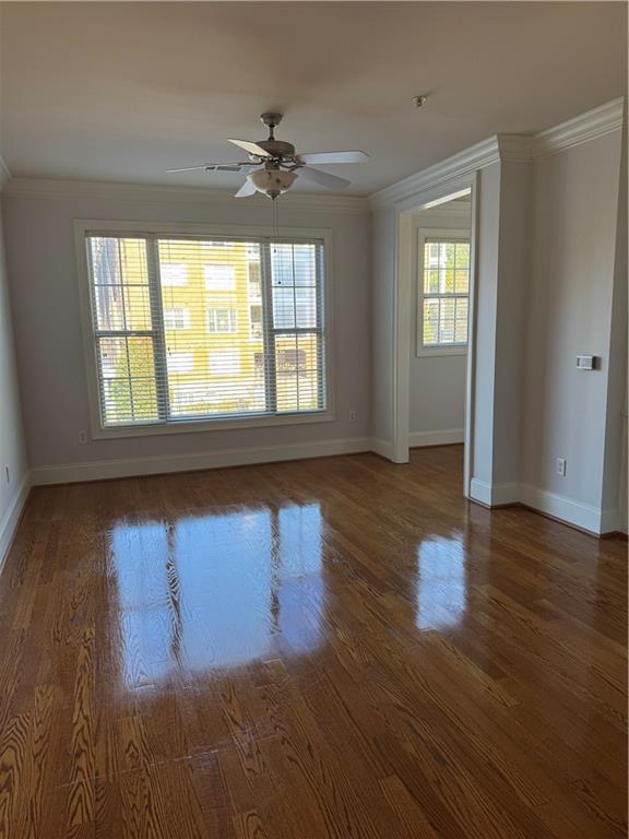 empty room featuring ornamental molding, ceiling fan, baseboards, and wood finished floors
