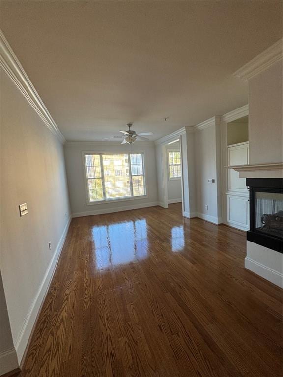 unfurnished living room with crown molding, a ceiling fan, a multi sided fireplace, wood finished floors, and baseboards