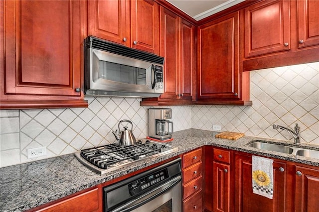 kitchen featuring stainless steel appliances, sink, decorative backsplash, and dark stone counters