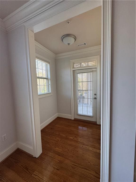 doorway with a healthy amount of sunlight, visible vents, crown molding, and wood finished floors