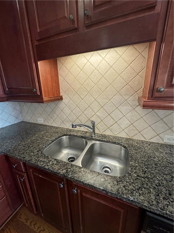 kitchen with tasteful backsplash, dark stone countertops, and a sink
