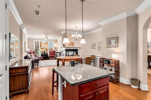 kitchen with ornamental molding, a kitchen island, and light hardwood / wood-style floors