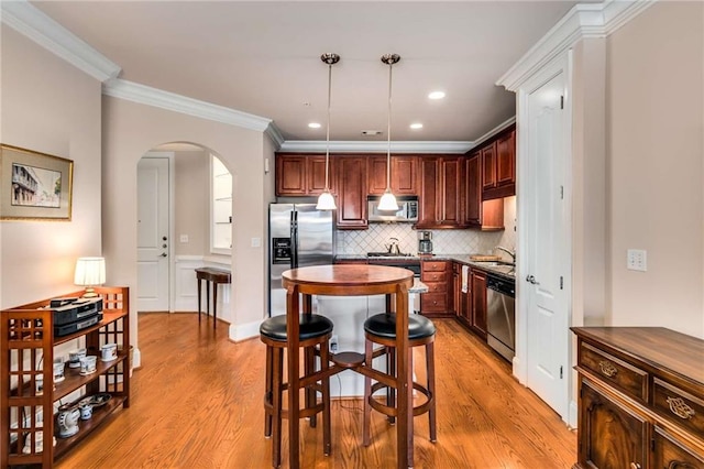 kitchen with appliances with stainless steel finishes, decorative light fixtures, sink, decorative backsplash, and crown molding